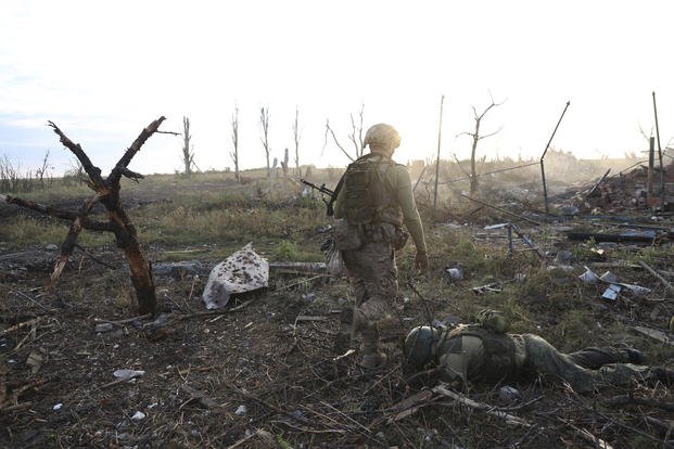 Assault unit commander from the 3rd Assault Brigade who goes by the call sign 'Fedia,' passes by the body of a dead Russian soldier