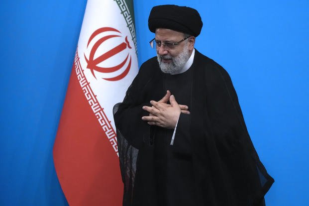 Iranian President Ebrahim Raisi places his hands on his heart as a gesture of respect
