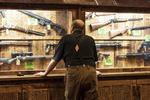 A man looks at cases of firearms in the halls of the Indianapolis Convention Center, where the National Rifle Association will hold its 148th annual meeting. (Lisa Marie Pane/AP File Photo)