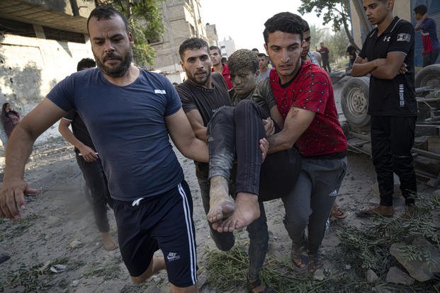 Palestinians carry a person wounded in Israeli airstrikes in Khan Younis, Gaza Strip