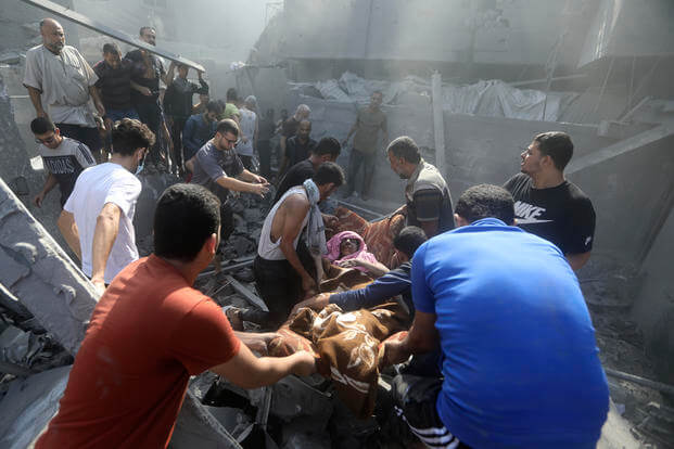 Palestinians carry an injured woman after being rescued from under the rubble of a destroyed building