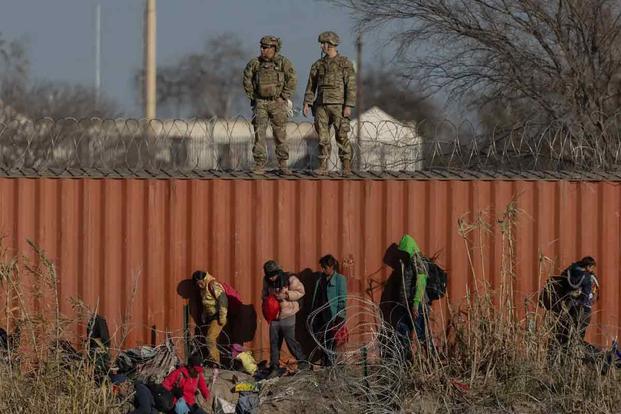 Migrants traverse the bank of the Rio Grande
