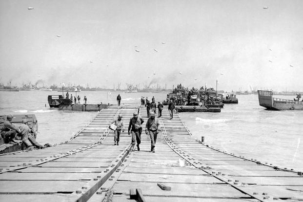 U.S. troops walk across a double-wide floating causeway at Omaha Beach in 1944. Source: Seabee Museum. Seabee Museum