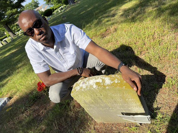 Darren Sands poses by the gravestone of his great-great-great-great-grandfather.