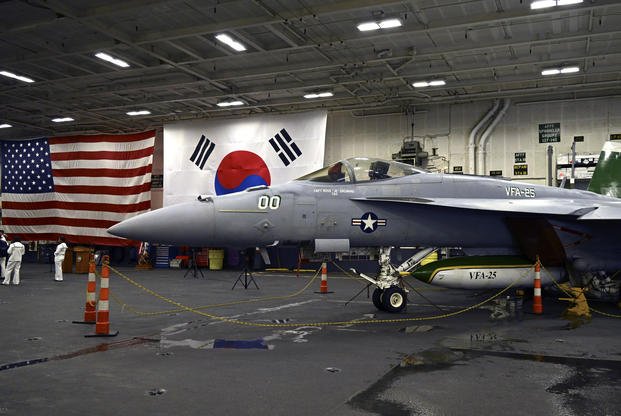An F-18 fighter jet sits in the hanger of the USS Theodore Roosevelt 