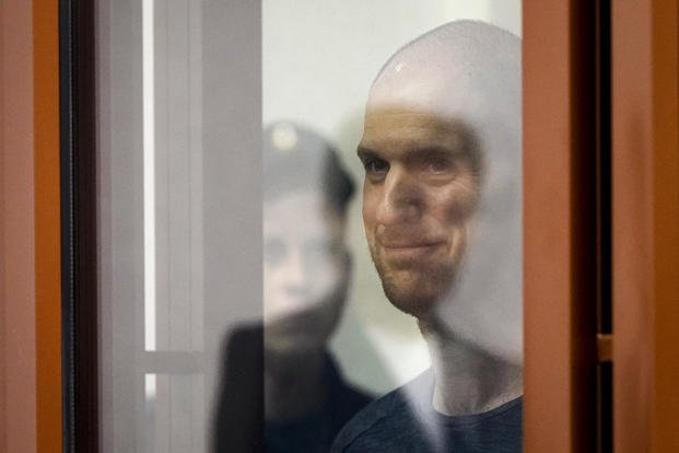 Wall Street Journal reporter Evan Gershkovich stands listening to the verdict in a glass cage of a courtroom