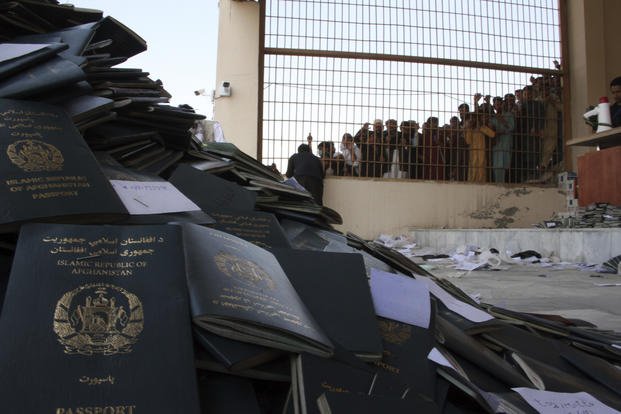 Afghans wait to collect their passports in the city of Jalalabad