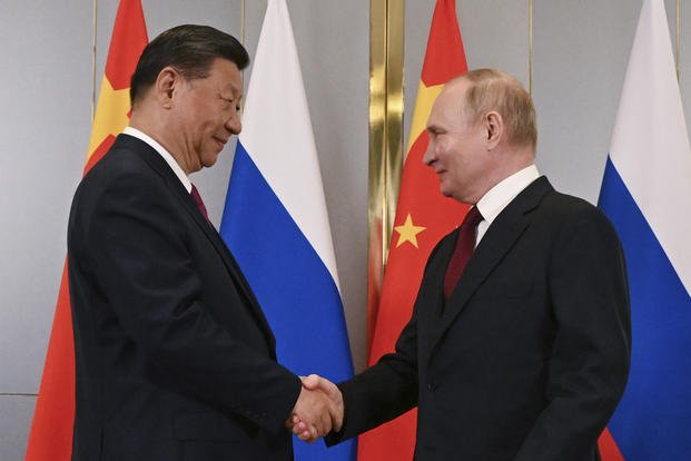 Russian President Vladimir Putin, right, and Chinese President Xi Jinping shake hands