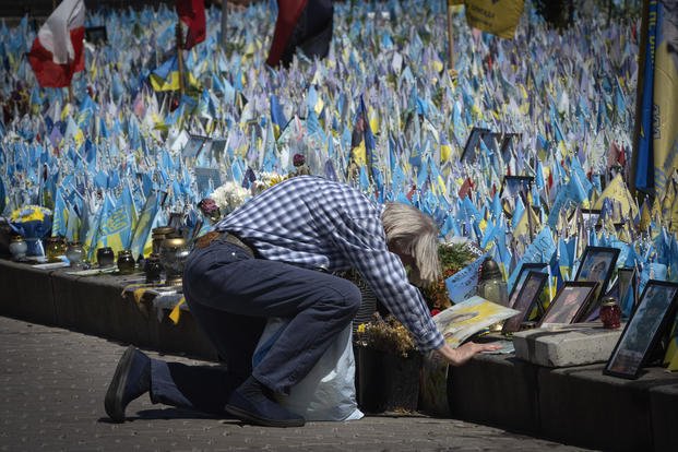 A man kneels in front of a makeshift memorial for fallen Ukrainian soldiers on Independence Square