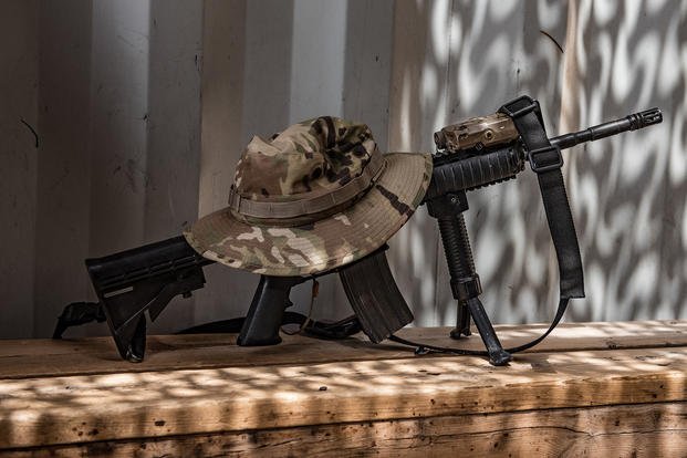 An M4 carbine and boonie cap sits near an airman on break at a security forces guard shelter in Southwest Asia. 