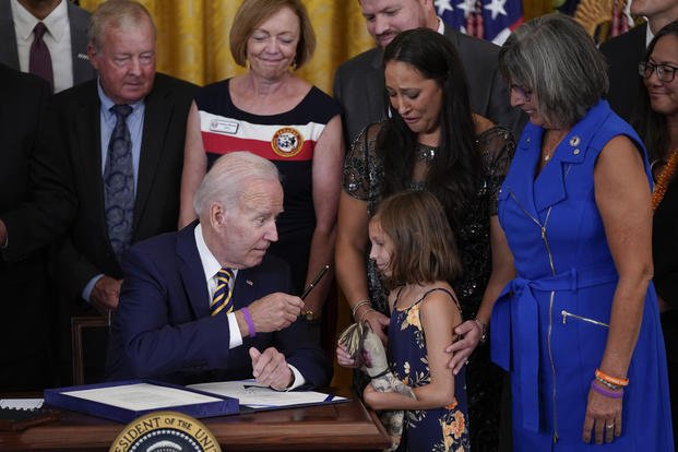 President Joe Biden gives the pen he used to sign the "PACT Act of 2022" to Brielle Robinson