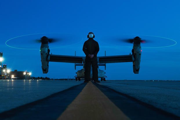 Marine awaits confirmation before marshaling a MV-22B Osprey to the runway on Peterson AFB