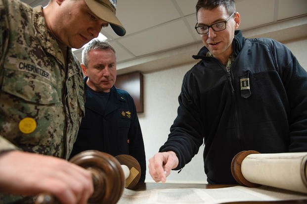 Rabbi Warren Yonatan, right, reads the Talmud to chaplain Les Skikorski, middle, and Lt. Cmdr. Rick Chernitzer during a Hanukkah celebration in the chapel aboard the aircraft carrier USS Dwight D. Eisenhower (CVN 69).