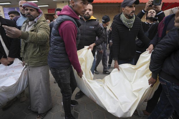 Palestinians carry white sacks containing the bodies of those killed in overnight Israeli airstrikes