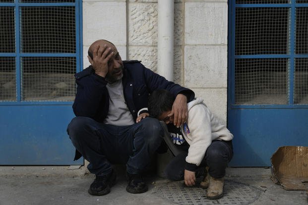 Mourners wait outside the morgue for the funeral of six Palestinians