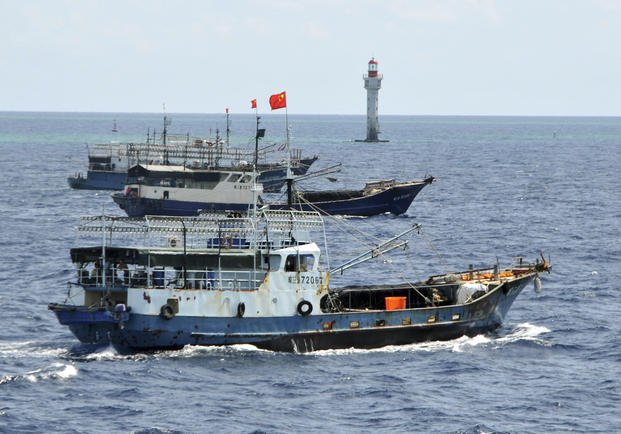Chinese fishing vessels navigate past a beacon in the Zhubi Reef off Spratly Islands in South China Sea