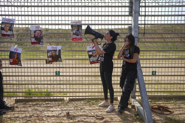 Relatives of hostages held by Hamas in the Gaza Strip, stand by the Israel-Gaza border fence