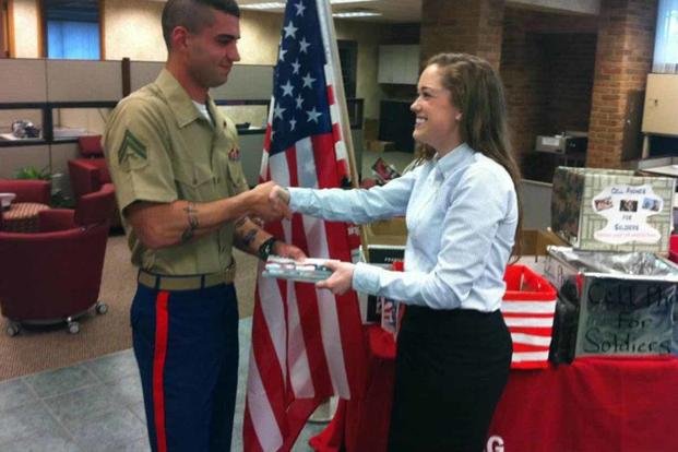 Brittany Bergquists hands a Marine a calling card during an event at a Bank of America location, recognizing the 200 locations that served as collection points for Cell Phones for Soldiers. (Cell Phones for Soldiers)