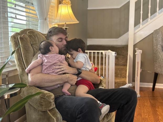 U.S. Marine Corps veteran Adrian Clouatre holds his 3-month-old daughter Lyn and his nearly two old son