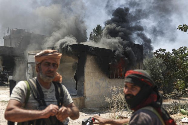 Bedouin fighters stand in front of a burned shop.
