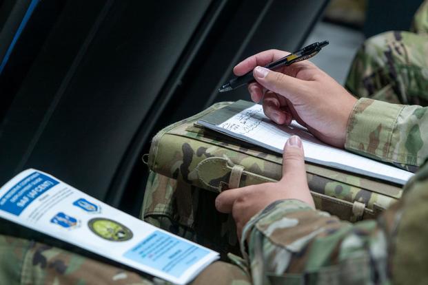 Service member writes in notebook. 