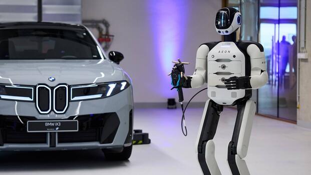 Humanoid Factory Robot standing next to BMW iX3 electric SUV