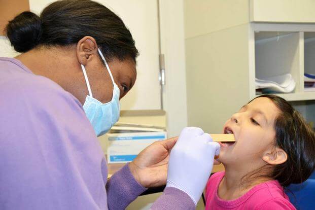 Capt. Adrienne Rembert, DDS conducts an oral screening for Reilli Wade, an Arnn Elementary first-grader, Feb. 20, during a preventative health visit for National Children's Dental Awareness Month. (U.S. Army / Candateshia Pafford)
