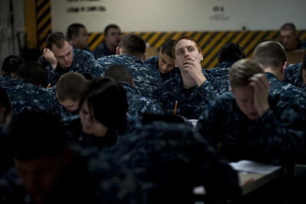 Navy sailors taking tests at desks.