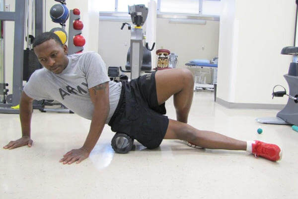 Spc. Reggie Wilson of the Raymond W. Bliss Army Health Center demonstrates the use of rollers for treating myofacial pain. (Photo Credit: Mo Greenberg)