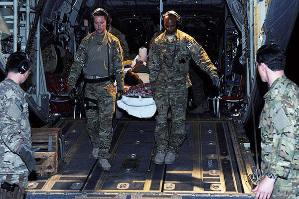 Tech. Sgts. Alexander Finn and Johnny Busby, both 455th Expeditionary Aeromedical Evacuation Squadron aeromedical evacuation technicians, transport a patient from a C-130 Hercules to an ambulance. (U.S. Air Force photo/SSgt. Whitney Amstutz)