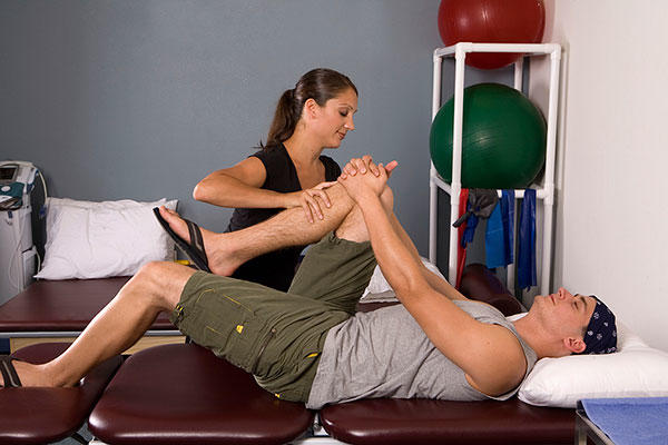 Physical therapist assists with stretches.