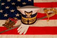 Officer's combination cover, sword, white gloves and medal rack laying upon an American flag. (U.S. Coast Guard photo)