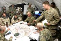 Capt. Timothy Cody, standing, briefs Col. Patrick O’Neal, commander of 2nd Armored Brigade Combat Team, and other leaders during a May 6 operations order at the National Training Center, Fort Irwin, California. (Matthew Cox/Military.com)