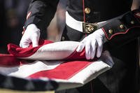 A U.S. Marine with Marine Forces Reserve folds the American flag during a military funeral