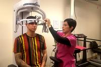 A physical therapist assistant at William Beaumont Army Medical Center adjusts the headpiece for a TBI patient.