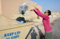 woman throwing trash into dumpster