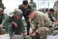 A U.S. Soldier assists Philippine Marines to inspect their equipment for a jump during Exercise Balikatan.