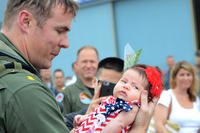 man in flight suit holding newborn