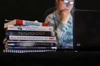 Stack of college textbooks with military member in background