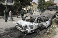 Security personnel inspect a damaged vehicle where rockets were fired from in Kabul, Afghanistan