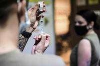 Aeromedical technician fills a syringe with the COVID-19 vaccine