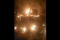 People walk by burning debris after an explosion of an oil tanker in Sierra Leone.