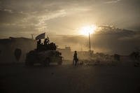 Taliban fighters ride atop a Humvee on the way to detain Afghans