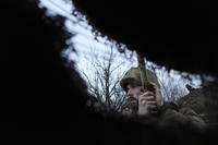 A Ukrainian serviceman listens to artillery shots standing in a trench. 