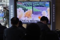 People watch a TV showing a file image of North Korea's missile launch.
