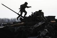 A Ukrainian serviceman walks on a destroyed Russian fighting vehicle in Bucha, Ukraine