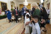 First lady Jill Biden, walks in the East Room with little caregivers.