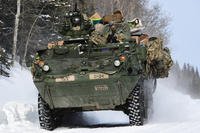 A Stryker vehicle moves down a snowy road.