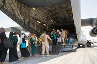 U.S. Marines  help Afghan evacuees board plane at Al Udeid Air Base.