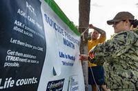 Nave sailors raise a banner for Suicide Awareness Month.